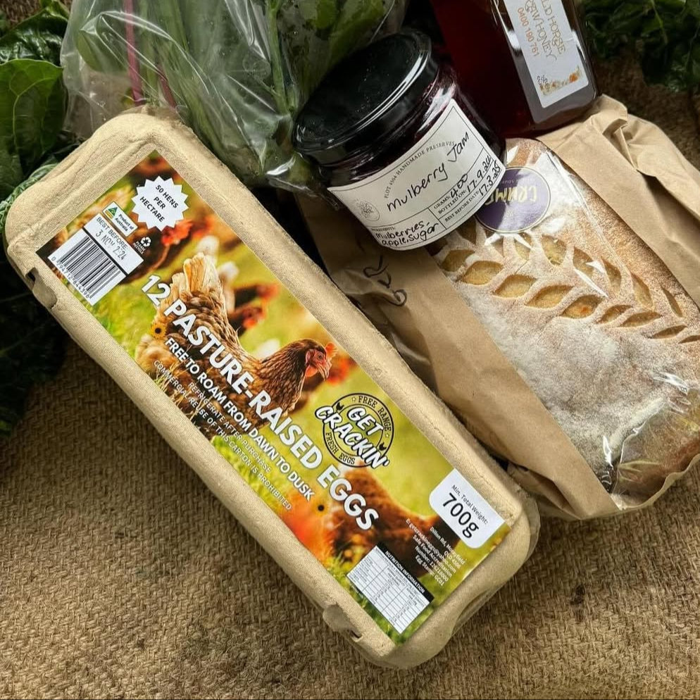 Carton of pasture-raised eggs with a jar of jam and bread on a textured surface