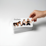 A minimalist product photo featuring a hand gently holding a stack of rounded-edge A6 thank-you postcards. The top card reads “thank you for your order”